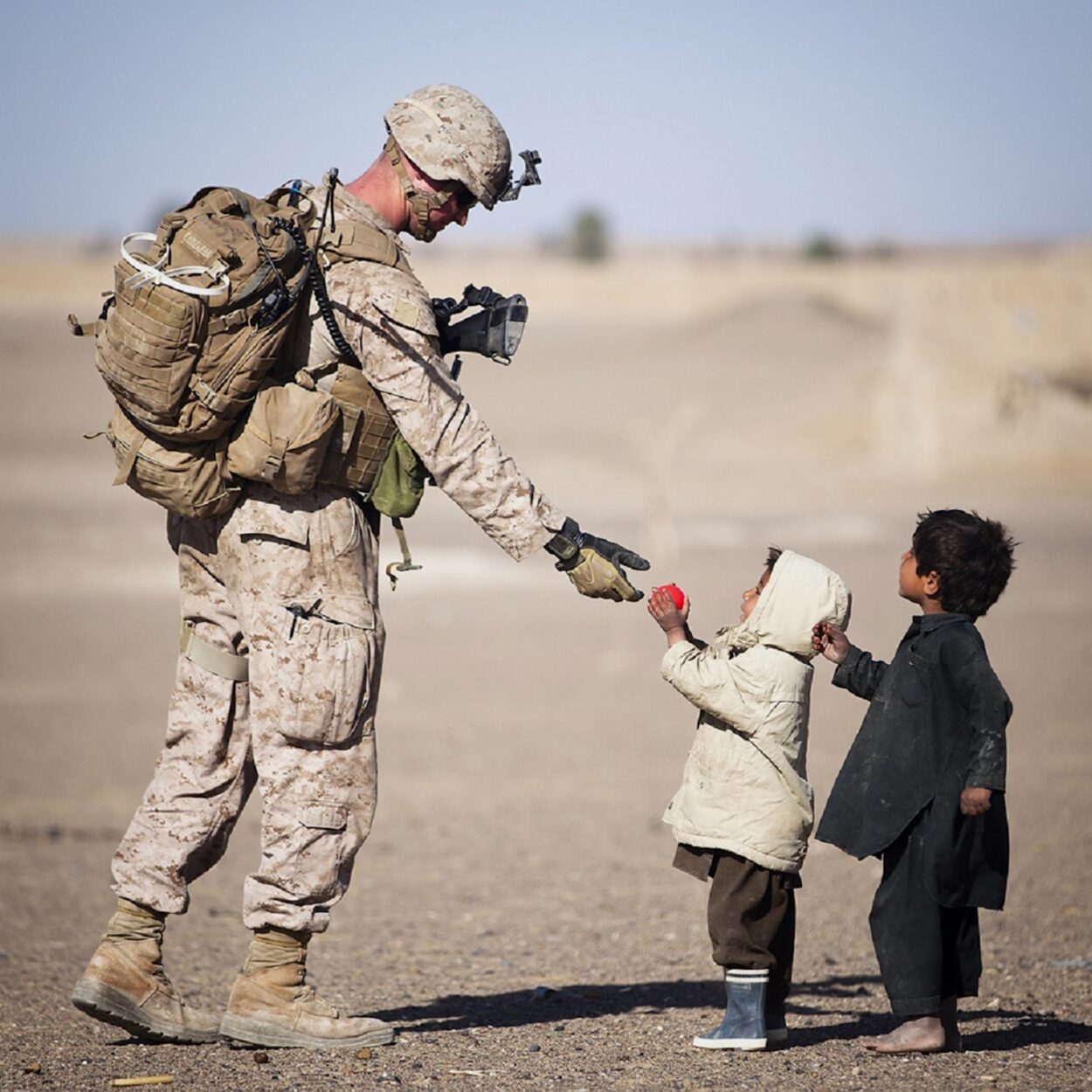 Soldier Giving Red Fruit on 2 Children during Daytime