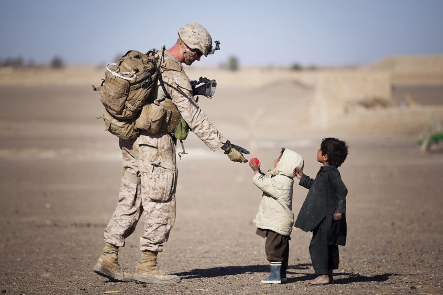 Soldier Giving Red Fruit on 2 Children during Daytime