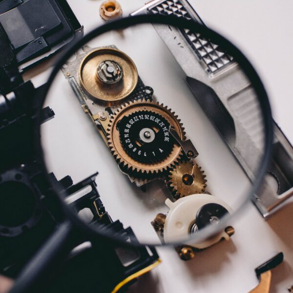 person using magnifying glass to see gold and white device gear