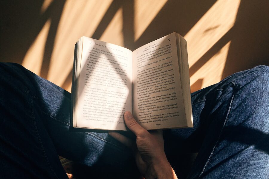 person holding book sitting on brown surface